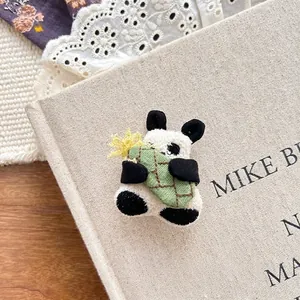 Close-up of cute 3D plush panda hair clip resting on a vintage linen book cover