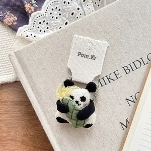 Detail of cute plush panda hair clip with bamboo leaf decor on Pom.Ki card