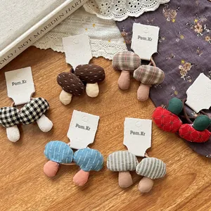 Detail of assorted handmade fabric mushroom hair ties on display cards in rustic setting