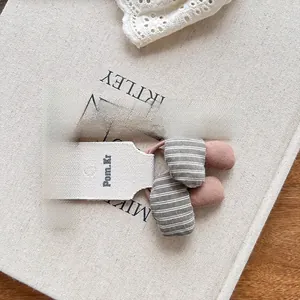 Close-up of pink and grey fabric mushroom hair tie showing size with wooden ruler