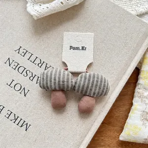 Close-up of handmade fabric mushroom hair ties with grey-green stripes and pink cotton stems