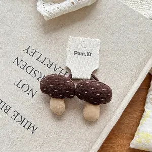 Close-up of handmade mushroom fabric hair ties with white embroidery detail on a card