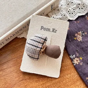 Detail einer handgefertigten Pilz-Haarklammer auf einer Vintage-Beigekarte für Mädchen