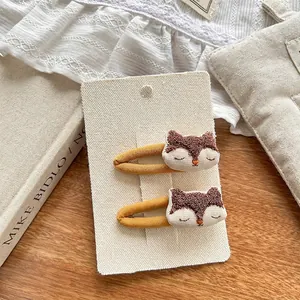 Detalle de pinzas para el cabello bordadas de zorro para niños en tarjeta de marca