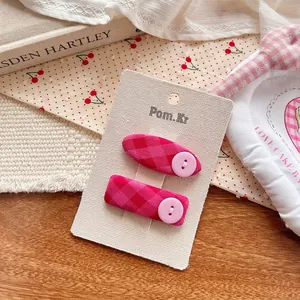 Détail de pinces à cheveux à carreaux roses avec boutons sur carte de présentation