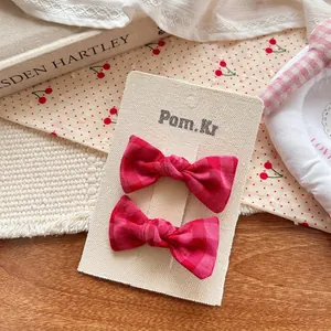 Paire de barrettes à nœud à carreaux rouges sur carte avec dentelle et tissu doux