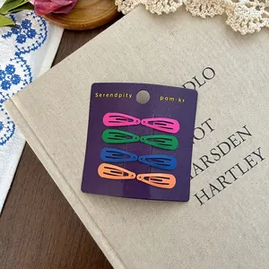 Set of 8 colorful matte metal BB hair clips in vibrant colors on a vintage book backdrop