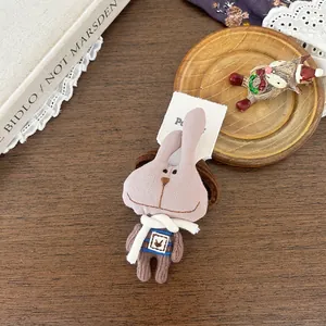 Détail d'un chouchou lapin en peluche rose avec tenue rayée dans un emballage de luxe