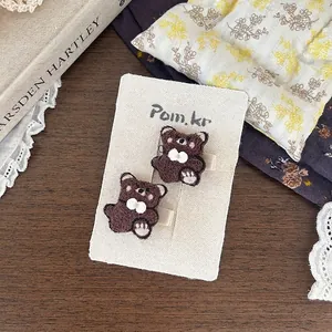 Dettagli di due fermagli per capelli a forma di orso di peluche con fiocchi bianchi