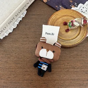 Gros plan d'un accessoire ours en peluche avec vêtements rayés bleus sur table en bois