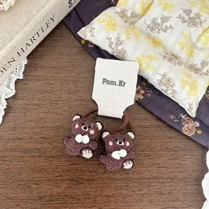 Primo piano di elastici per capelli a forma di orsetto di peluche marrone su tavolo in legno