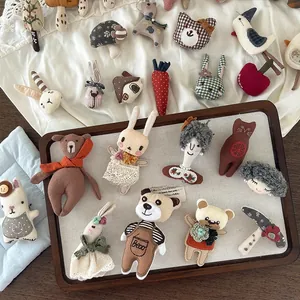 Detailed view of handmade fabric animal brooches with lace accents and cute embroidery