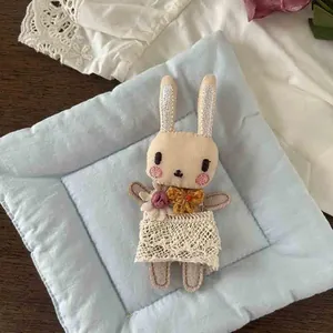 Detailed embroidery and lace trim on a handmade cotton rabbit doll brooch accessory