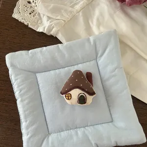 Detail of a handmade stuffed mushroom house fabric brooch with intricate embroidery