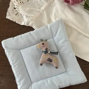 Detail view of a handmade fabric giraffe brooch featuring embroidery and blue ribbon accents