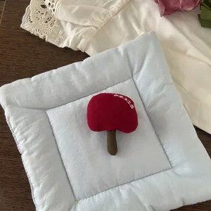 Detail shot of a handmade red fabric mushroom brooch on a light blue display pad
