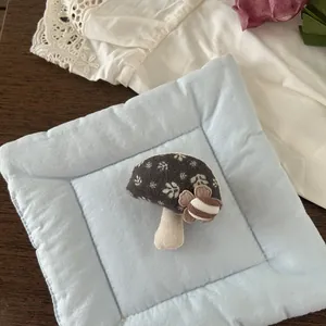 Detail of a handmade mushroom fabric brooch featuring cotton linen texture and floral decor