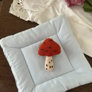 Detail of handmade fabric mushroom brooch with red-brown cap and hand-stitched details