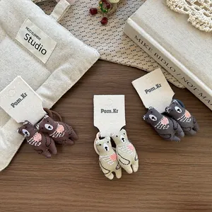 Détail de broderie d'ours mignon sur des élastiques à cheveux en coton marron et beige