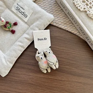 Détail de pinces à cheveux ours brodées avec cœurs roses sur carte de présentation en tissu
