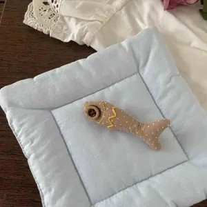 Detail of a handmade fish-shaped fabric brooch with white polka dots and button eyes