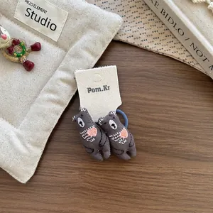 Détail d'élastiques ours en peluche gris avec broderie cœur rose sur carte de toile