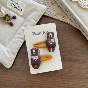Détail de jolies barrettes ours marron brodées sur carton avec décor en bois chaleureux