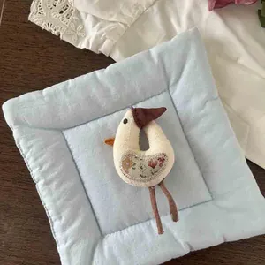 Close-up of handmade white plush goose brooch with floral patch and cotton fabric details