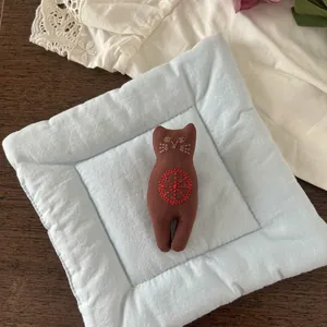 Detail of handmade brown fabric cat brooch with red embroidery and blue quilted pad