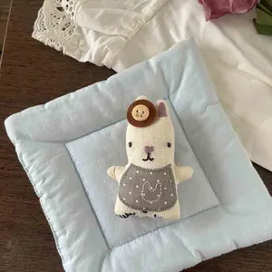 Close-up of cute plush bunny charm with polka dot bib and quilted blue pad accessory