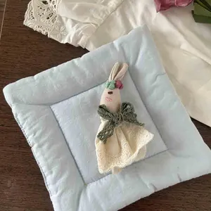 Close-up of handmade cartoon rabbit plush doll with lace dress on quilted pad
