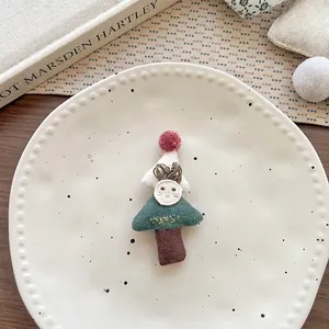 Vista macro di una spilla a forma di albero di Natale fatta a mano su piatto di ceramica