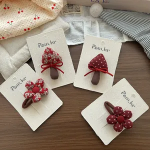 Dettaglio di elastici per capelli fatti a mano con funghi e fiori in tonalità rosso scuro