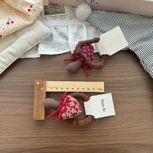 Dettaglio di elastici per capelli a fungo in tessuto rosso a pois su righello legno