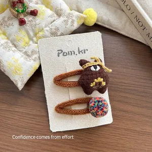 Gros plan sur une pince à cheveux ours en tricot et des clips pompons sur carte