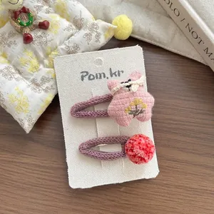 Détail de barrettes tricotées violettes faites main avec étoile rose et pompon
