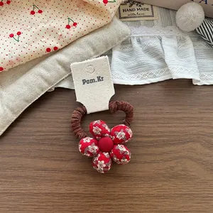 Dettaglio di un elastico per capelli fatto a mano in tessuto a fiori rossi e marrone