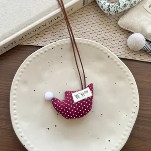 Dettaglio della collana albero in tessuto rosso a pois con pompon bianchi e W.H.M