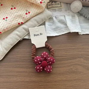 Dettaglio dell'elastico per capelli a fiori rossi a pois su cartoncino elegante