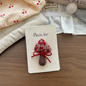 Dettaglio di un accessorio per capelli a fungo in tessuto floreale rosso fatto a mano su carta