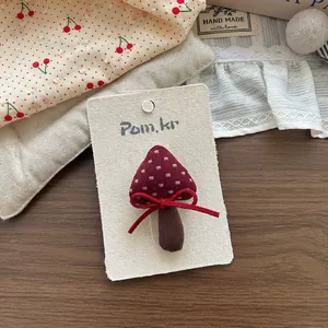 Dettaglio dell'accessorio per capelli in tessuto a forma di fungo su cartoncino espositivo
