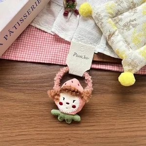 Detail of cute pink plush strawberry hair tie with embroidery on a cozy wooden background