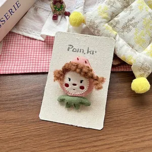 Detailed view of handmade strawberry girl fabric brooch on a white brand display card