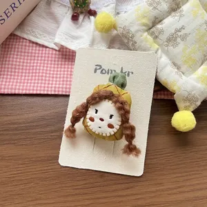 Detail of handmade fabric hair clip featuring a cute girl with a green plaid hat and braids