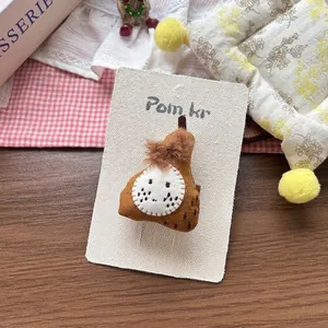 Detailed close-up of a handmade brown fabric pear hair clip on a white display card
