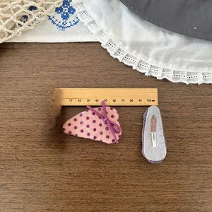 Détail de pinces à cheveux à pois roses faites main avec mesure sur fond de bois