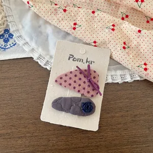 Vue détaillée des barrettes en tissu à pois roses et rose grise sur carte de présentation