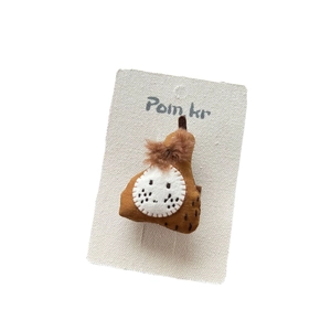 Cute brown plush pear hair accessory on a white display card for girls and toddlers