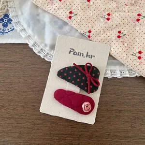 Détail de pinces à cheveux en tissu rouge à fleurs et pois sur carte d'exposition