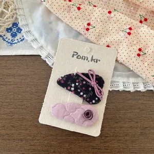 Détail de barrettes à motifs floraux et épingles matelassées roses sur carte